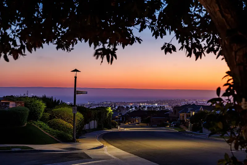Street view down toward the harbor at dusk — Corona del Mar real estate photography