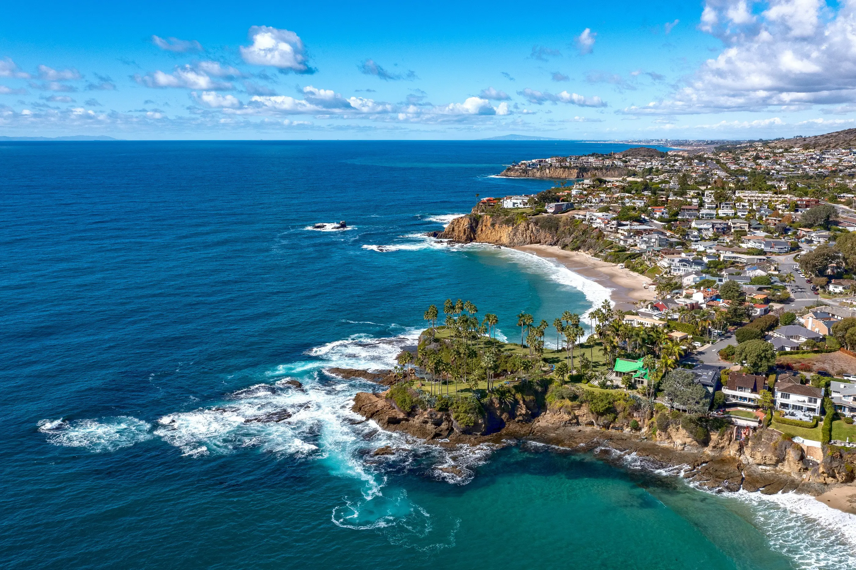 Aerial view of the Laguna Beach coastline, with cliffs, a cove, and coastal homes above the water